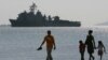 FILE - A Filipino family stroll the beach at Subic Bay as the USS Harpers Ferry approaches to dock, Feb. 17, 2006. 