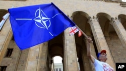მამაკაცი ნატოს და საქართველოს დროშებით, საქართველოს პარლამენტის შენობის წინ. 