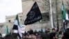 Para pengunjuk rasa membawa bendera Al-Qaeda dalam demonstrasi anti-pemerintah setelah salat Jumat di Kota Marat Numan di Provinsi Idlib, Suriah, pada 11 Maret 2016.