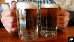 Arhiva- Barmen poslužuje dve krigle piva u taverni u Montpeliru, Vermont, 29. juna 2004.