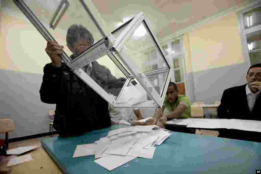An election worker empties a ballot box to count votes after parliamentary elections at a polling station in Algiers, Algeria, May 10, 2012.