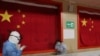 身穿防护服的医护人员在武汉的一所方舱医院里安慰一名病患。（2020年2月27日）