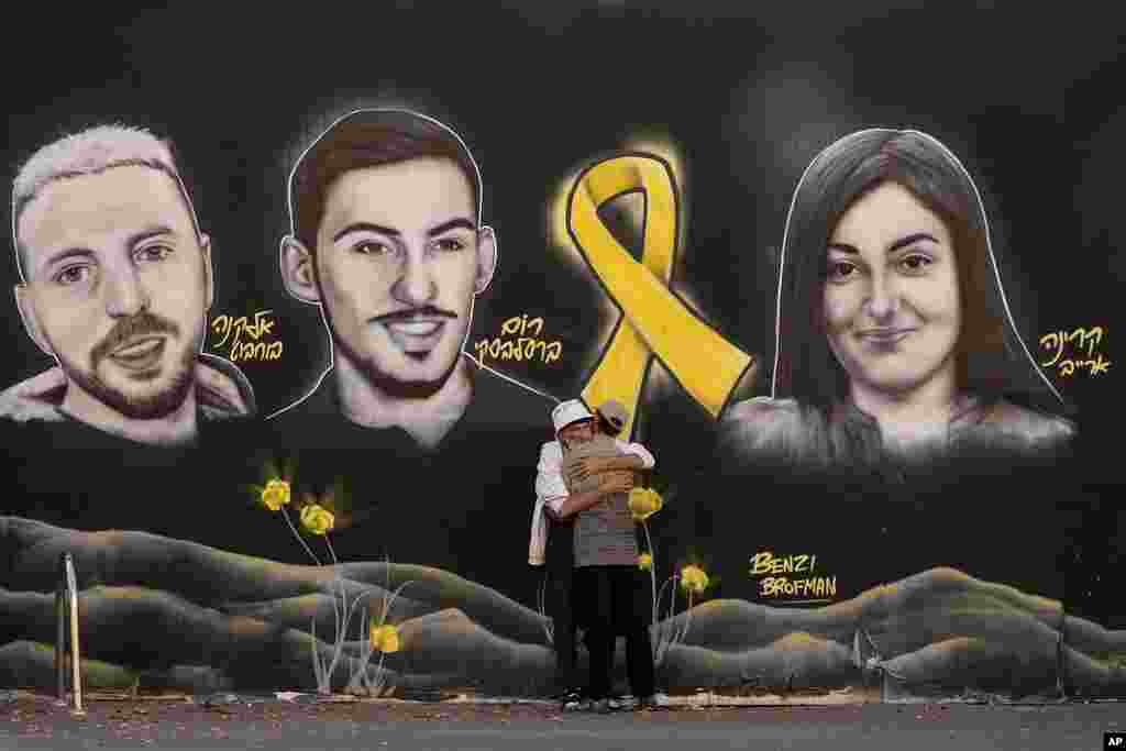 People hug next to graffiti portraits of Gaza-held hostages in Jerusalem. (AP Photo/Ohad Zwigenberg)