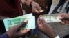 Zimbabweans compare the new note with the U.S. dollar note following the introduction of new notes by the Reserve Bank of Zimbabwe in Harare, Nov, 28, 2016. 