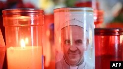 Lilin dinyalakan di patung Yohanes Paulus II di luar Rumah Sakit Universitas Gemelli tempat Paus Fransiskus dirawat karena pneumonia, di Roma, Selasa, 4 Maret 2025. (Foto: Alberto Pizzoli/AFP)