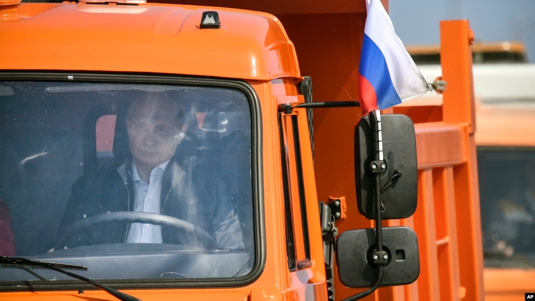 Russian President Vladimir Putin drives a truck to officially open the much-anticipated bridge linking Russia and the Crimean peninsula, during the opening ceremony near in Kerch, Crimea, Tuesday, May 15, 2018. (Alexander Nemenov/Pool Photo via AP)