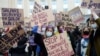 FILE - Women hold placards during a demonstration to call for gender equality and demand an end to violence against women, on International Women's Day in Brussels, Belgium, March 8, 2021. 