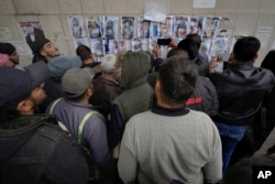 Ljudi posmatraju fotografije i tragaju za nestalim članovima svojih porodica, na zidu bolnice Al-Mujtahid u Damasku, 11. decembra 2024. (Foto: AP/Hussein Malla)