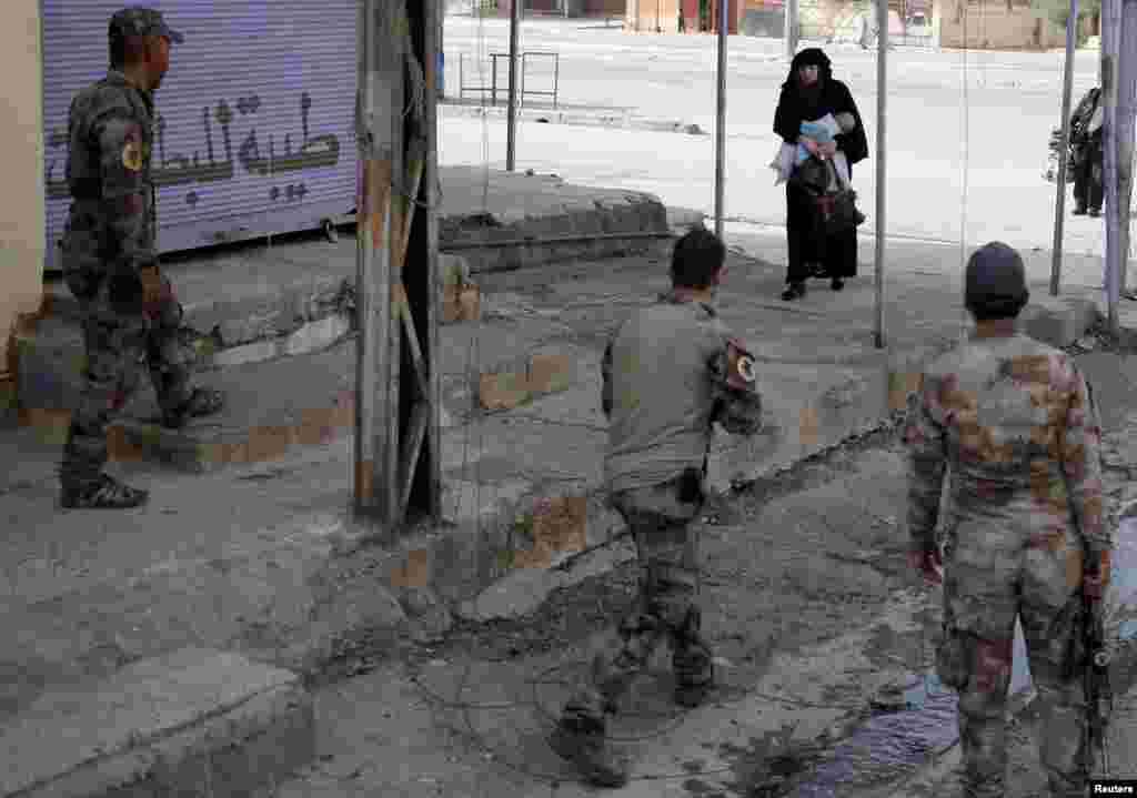 A woman holds her child as she crosses from a part of Mosul controlled by Islamic State fighters into an area n Mosul run by Iraqi special forces soldiers.
