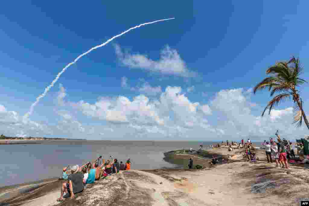 People take photos of an Ariane 5 space rocket with a payload of four Galileo satellites as it lifts off from ESA's European Spaceport in Kourou, French Guiana.