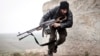 FILE - In this December 17, 2012 file photo, a Free Syrian Army fighter takes cover during fighting with the Syrian Army in Azaz, Syria.