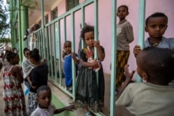Children displaced by the conflict play on metal railings at the elementary school where they now live with their families in the town of Abi Adi, in the Tigray region of northern Ethiopia Tuesday, May 11, 2021. (AP Photo/Ben Curtis)
