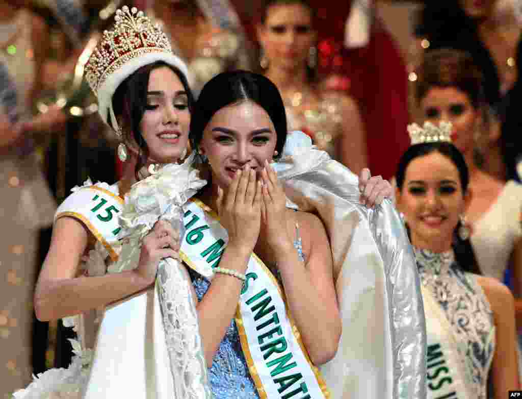 Newly elected 2016 Miss International Kylie Verzosa from Philippines (C) receives her gown from 2015 Miss International Edymar Martinez from Venezuela (L) during the Miss International beauty pageant final in Tokyo, Japan.