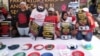 Para aktivis membawa poster-poster dan memamerkan barang-barang rumah tangga dalam demo di depan gedung DPR/MPR untuk menuntut DPR agar mengesahkan RUU Perlindungan Pekerja Rumah Tangga menjadi undang-undang, Jakarta, 14 Agustus 2023. (Foto: Tatan Syuflana/AP Photo)